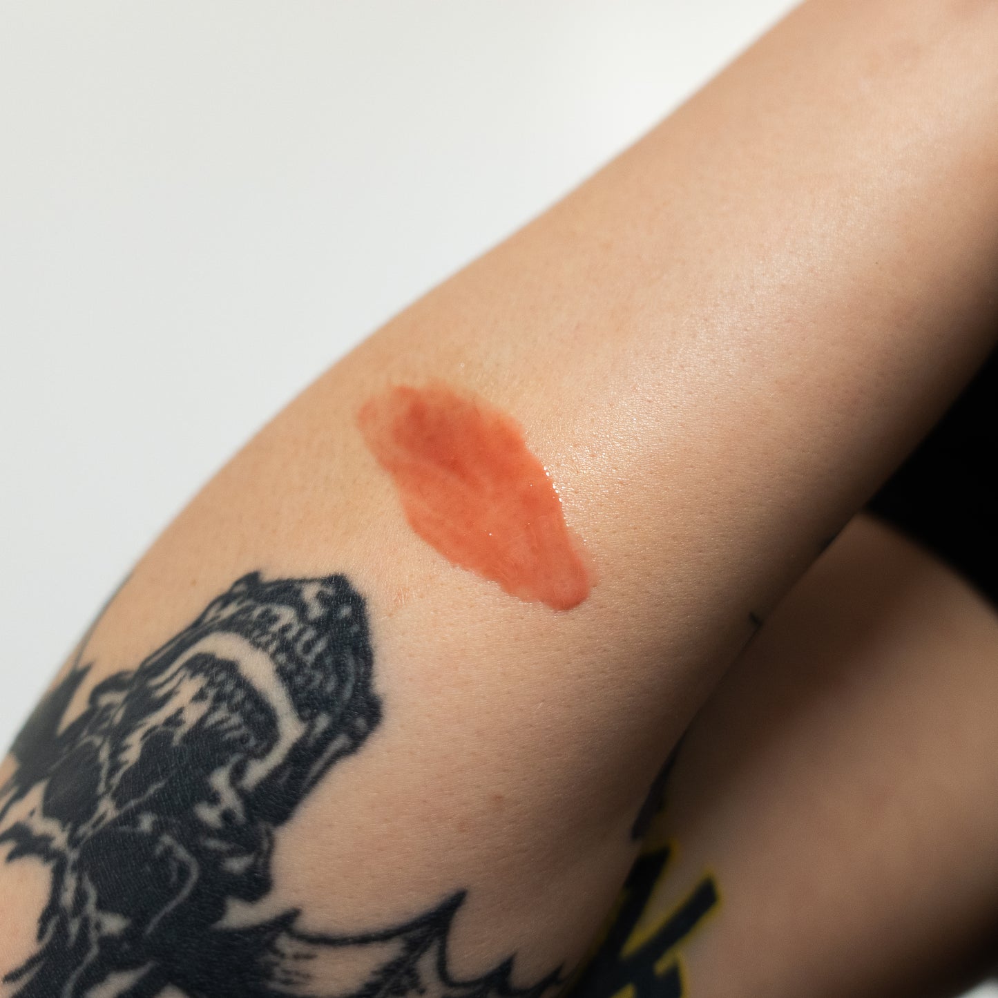 Close-up of a tattooed arm with a black ink design and a red mark.