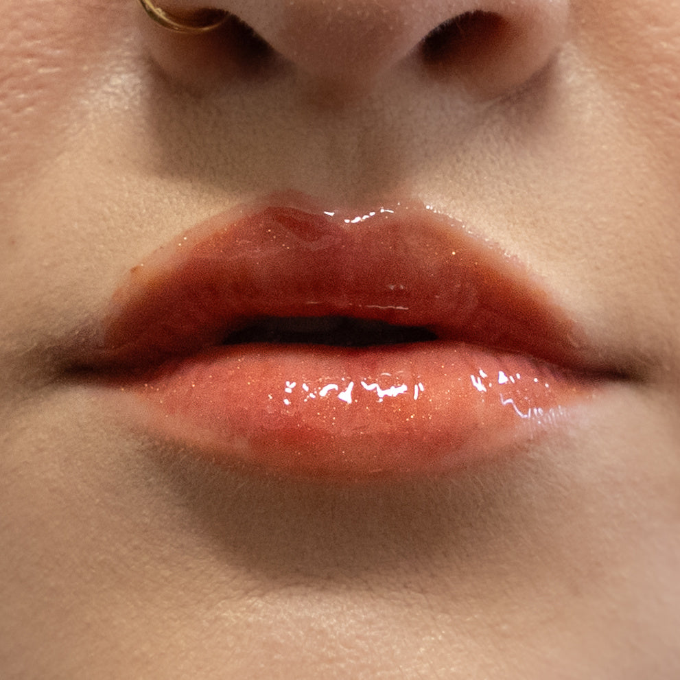 Close-up of a person's glossy lips with a neutral background