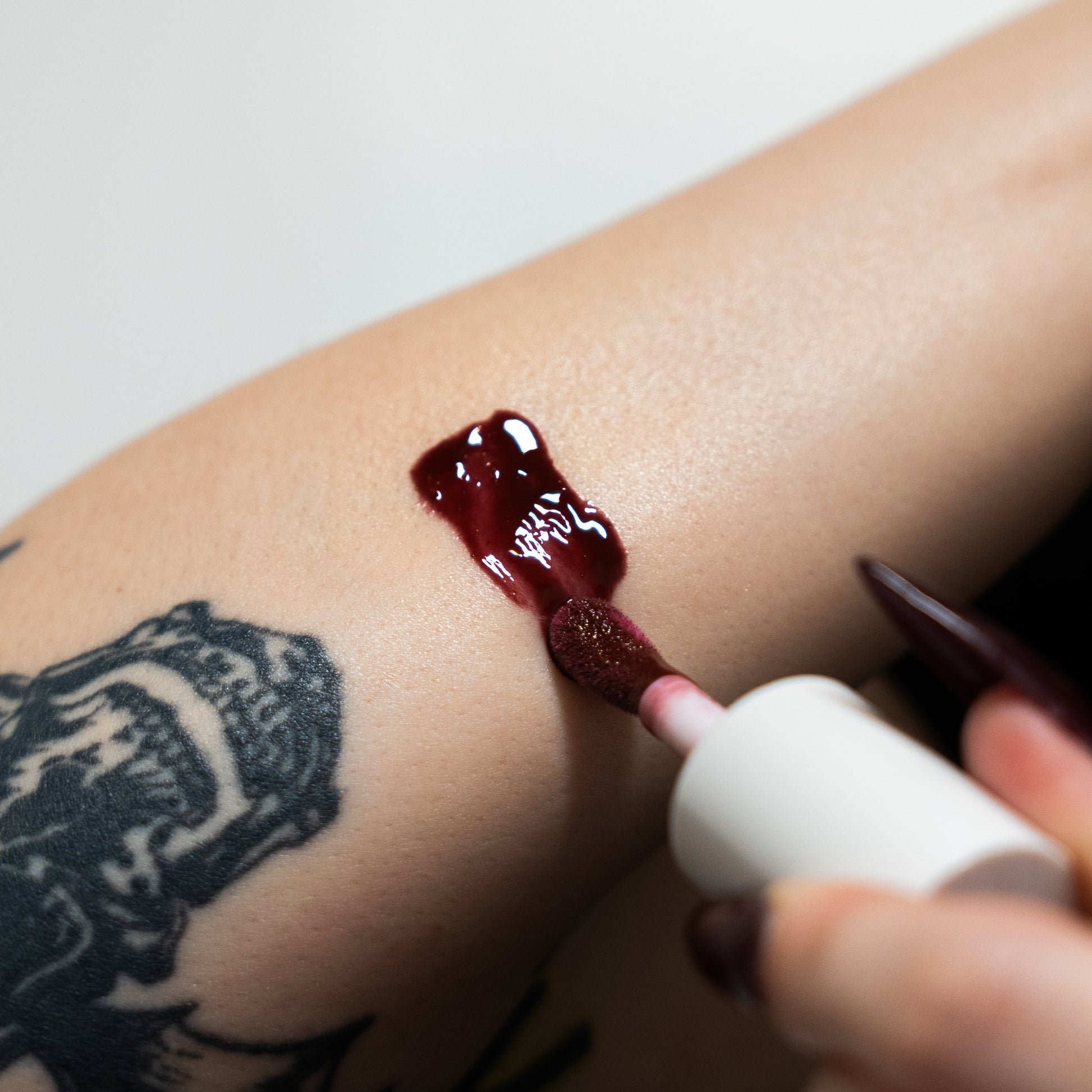 Red gel being applied to a person's arm with a small applicator.
