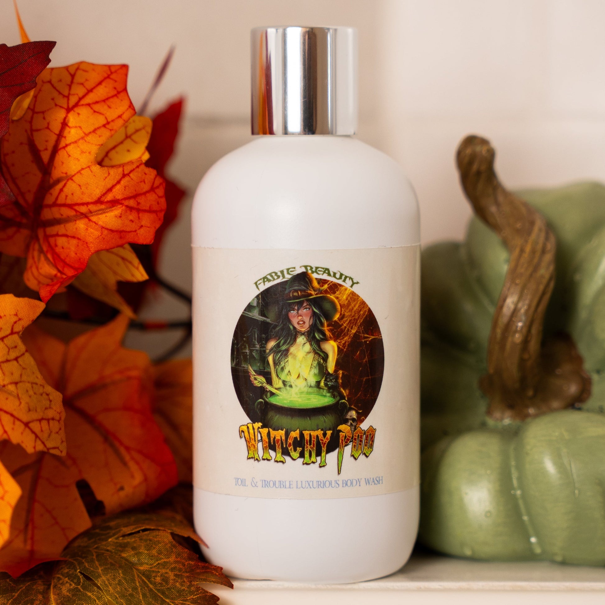 White bottle with a silver cap on a surface with autumn leaves and a green pumpkin.